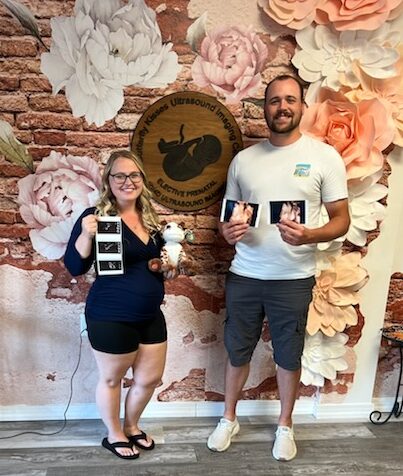 Happy family holding sonogram pictures at Butterfly Kisses Ultrasound Imaging Center.