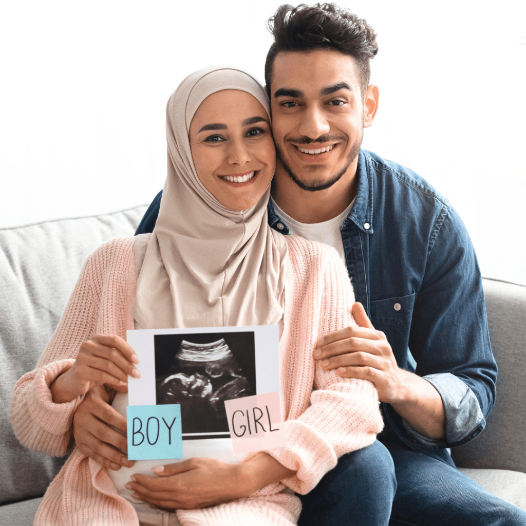 Couple holding baby ultrasound photo with boy or girl written on sides in pink and blue paper. Excited to reveal the baby gender.